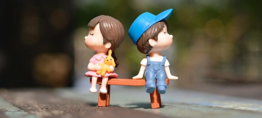 Boy and girl sitting on bench toy 1767434